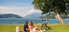 Ein Paar sitzt auf einer Picknickdecke am Ufer des Millstättersees